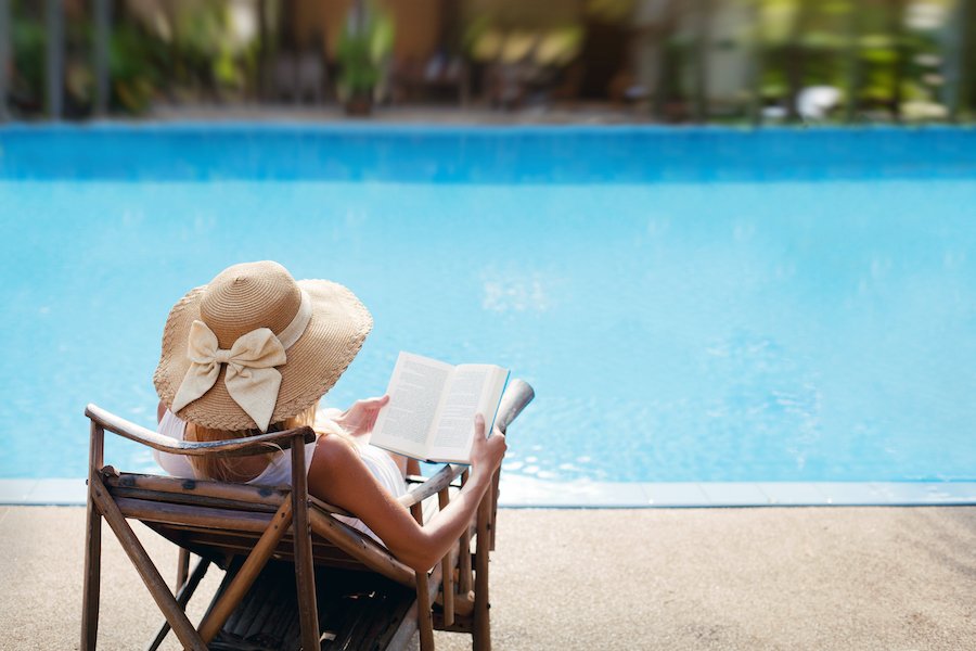 Une femme qui lit près de sa piscine