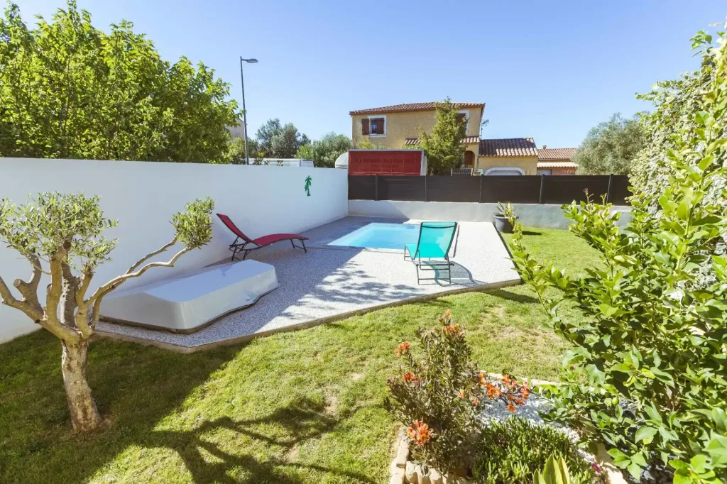Mini-piscine rectangulaire dans un jardin gazonné avec transats colorés