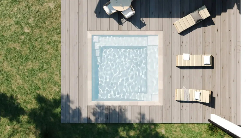 Vue aérienne d'une petite piscine carrée sur une grande terrasse en bois gris, entourée de transats, d'une table avec chaises et d'une pelouse verte