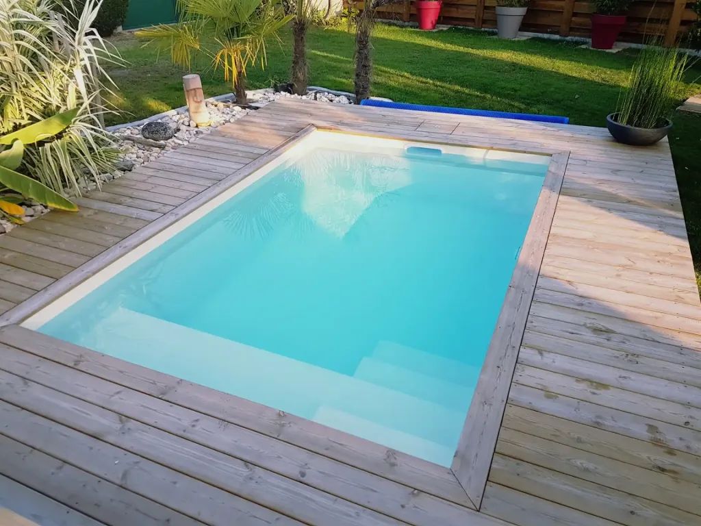 Mini-piscine rectangulaire turquoise sur terrasse en bois avec plantes exotiques