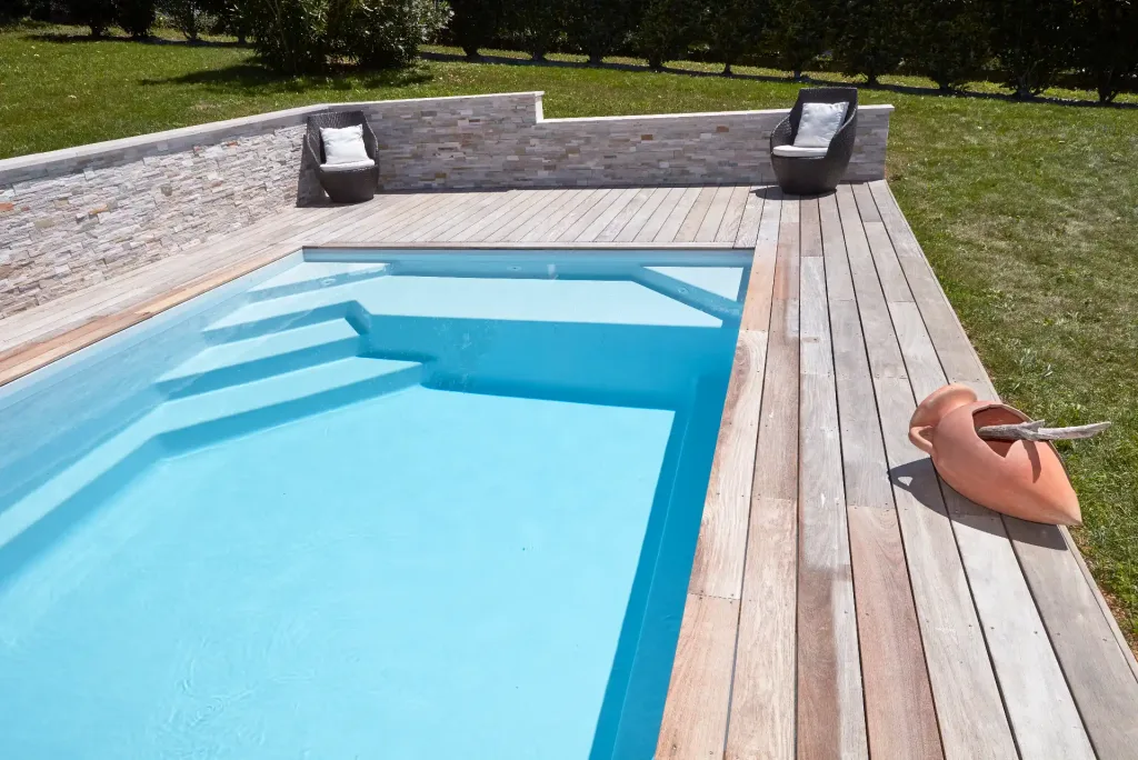 Piscine rectangulaire turquoise dans un jardin moderne avec terrasse en bois, salon extérieur et maison contemporaine