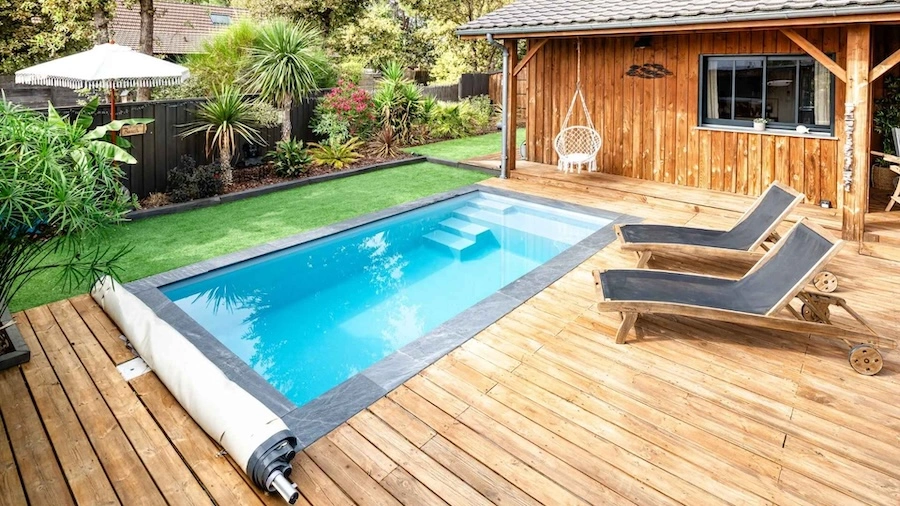 Uitzicht op een rechthoekig zwembad met polyester kuip, gelegen in een bloemrijke tuin