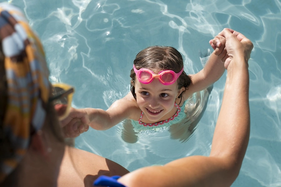 Enfant nageant dans une piscine privée familiale, illustrant l'importance de la sécurité et de l'assurance piscine pour les jeunes enfants