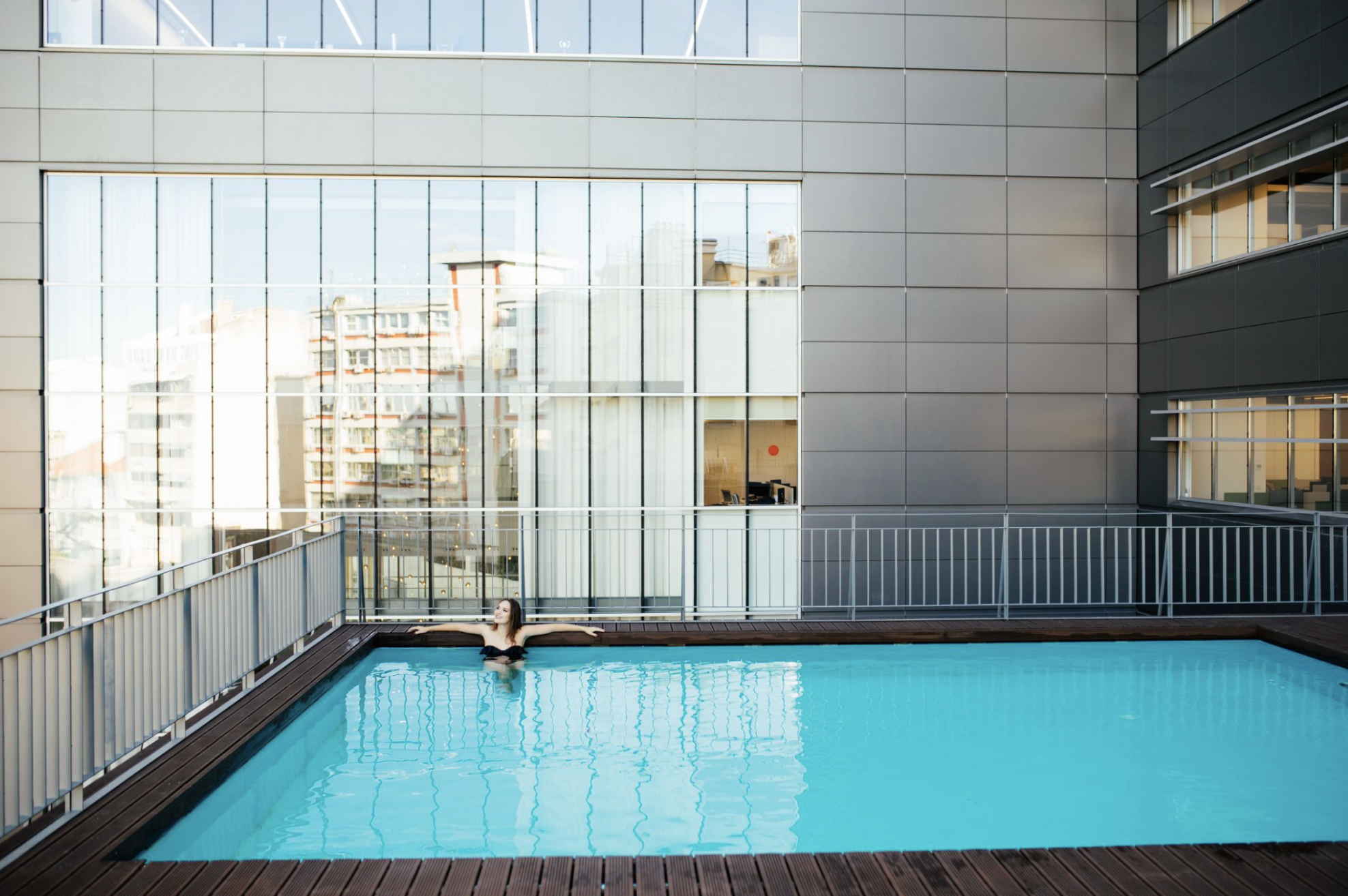 A swimmer relaxing in a communal pool on the terrace of a condominium building